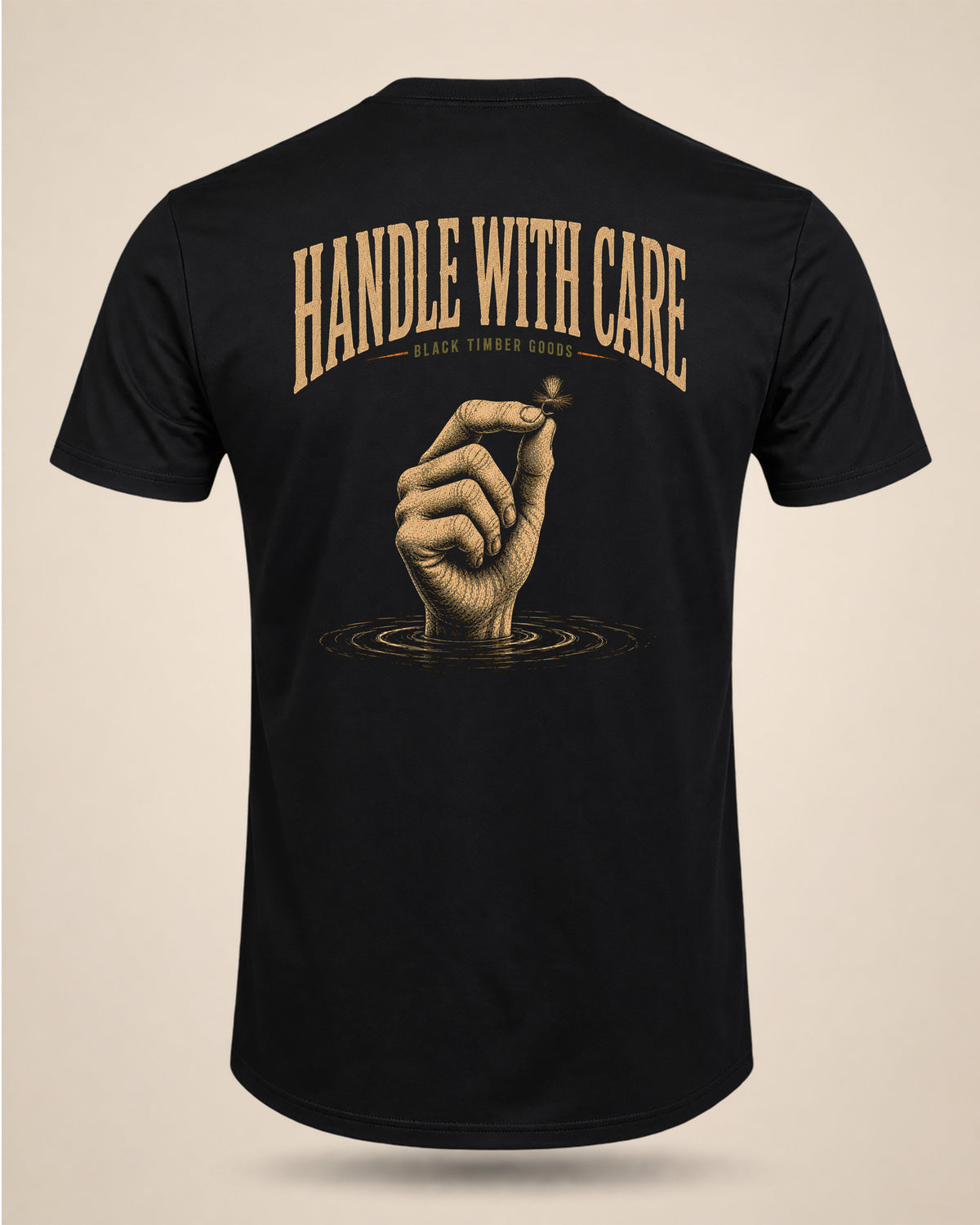 Black Handle With Care T-shirt featuring a hand holding a dry fly above water rings with the text Handle With Care.