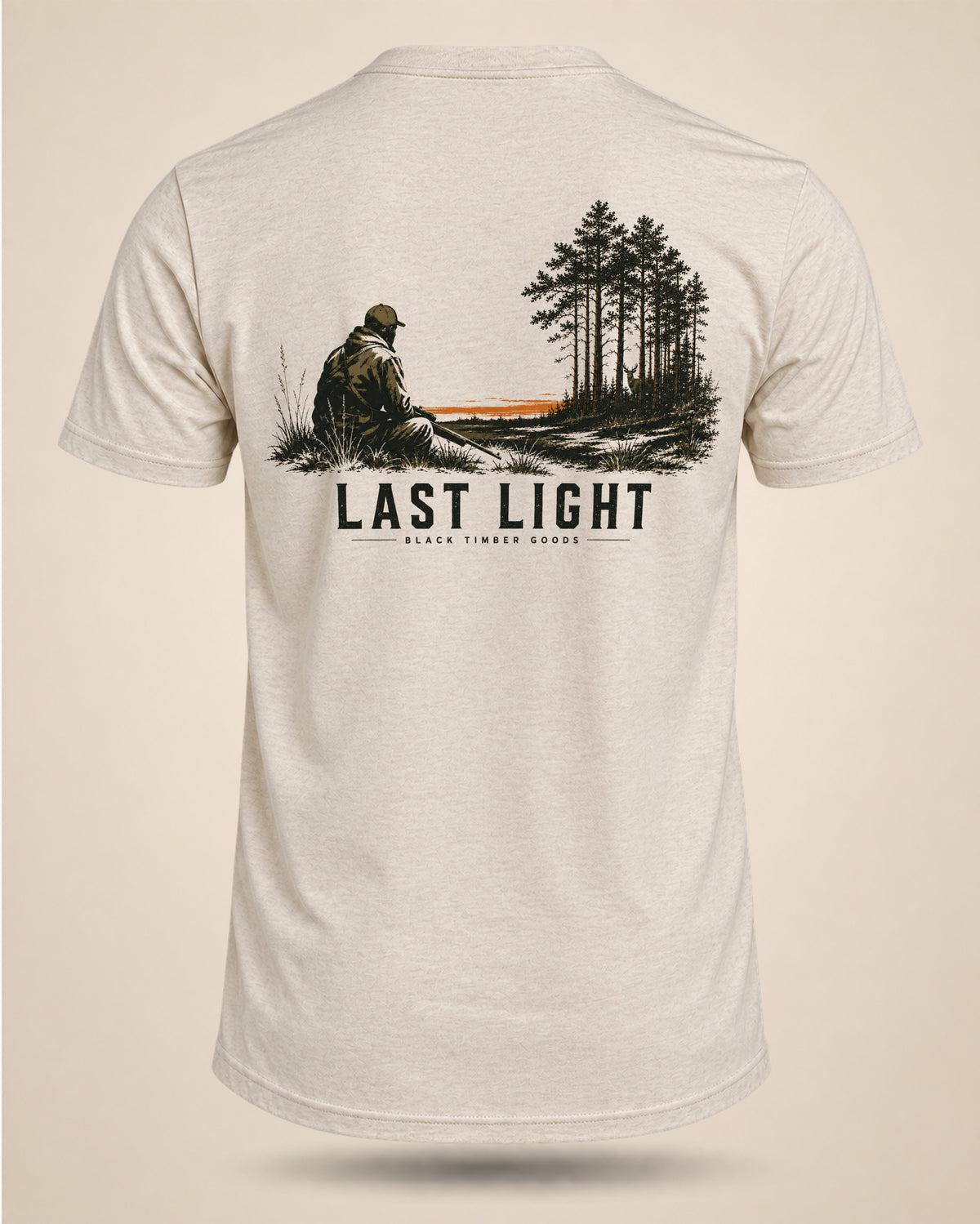 Cream Last Light hunting T-shirt featuring a seated hunter looking toward pine timber and a narrow band of sunset light.