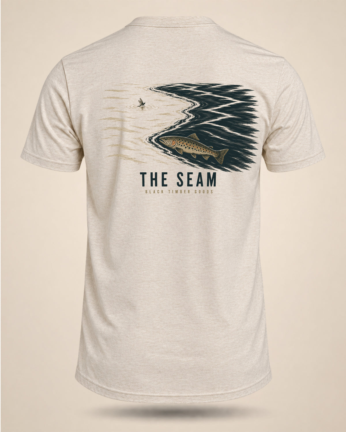 Cream The Seam fly-fishing T-shirt featuring a trout holding beside a dark current seam beneath a drifting insect.