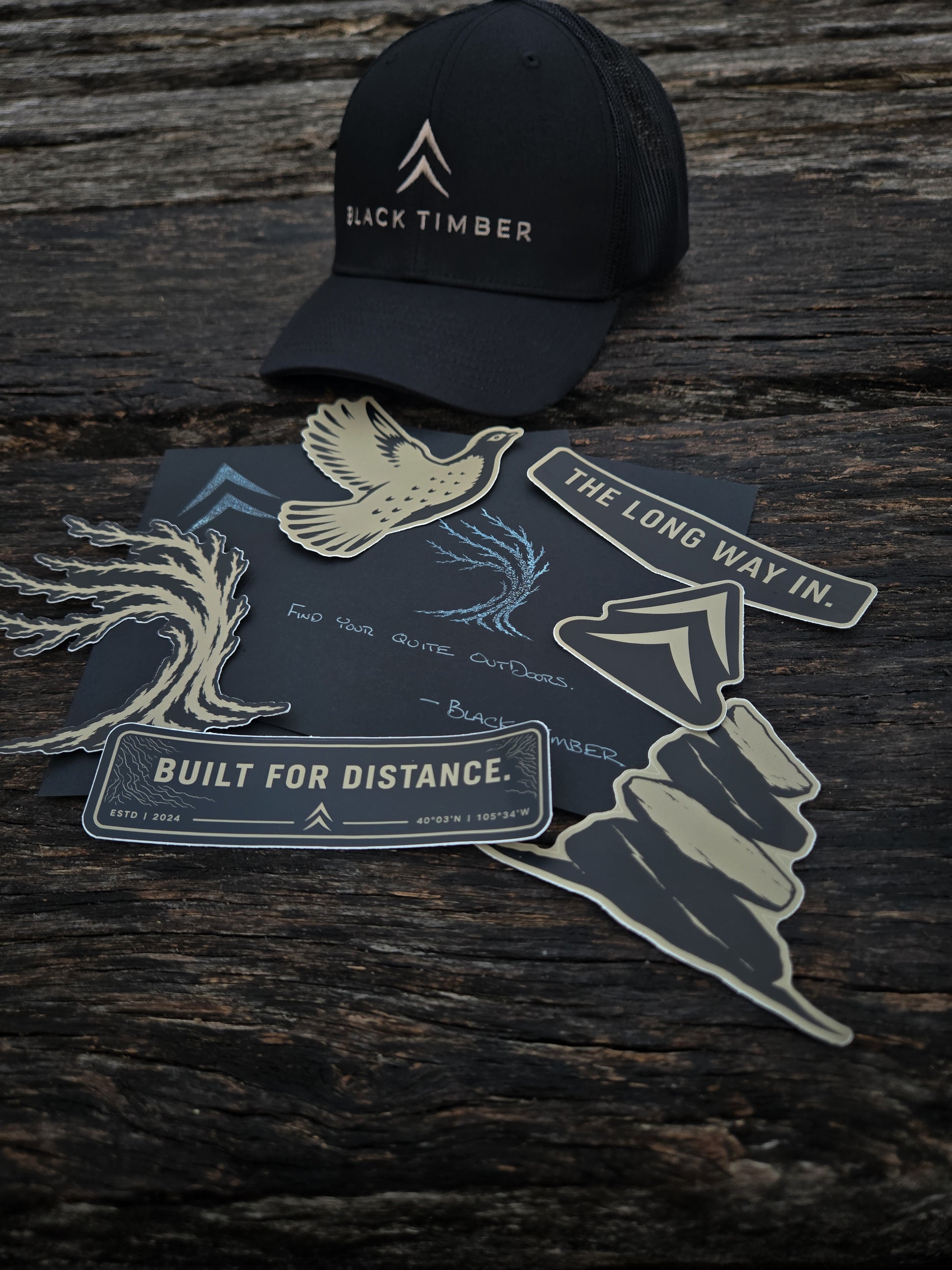 Black Timber Goods outdoor sticker collection displayed on weathered wood.