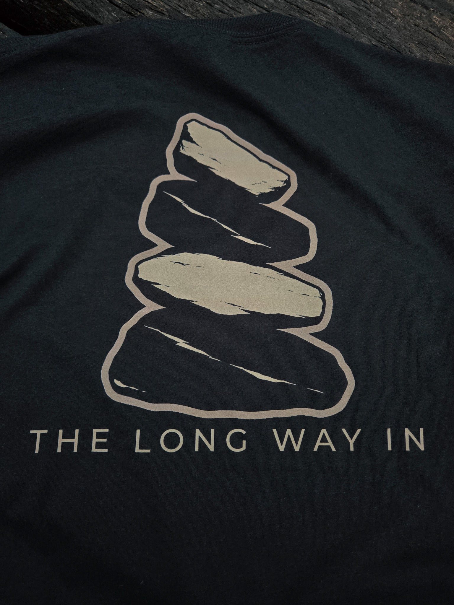 Close-up of The Long Way In weathered cairn artwork on the back of the shirt.