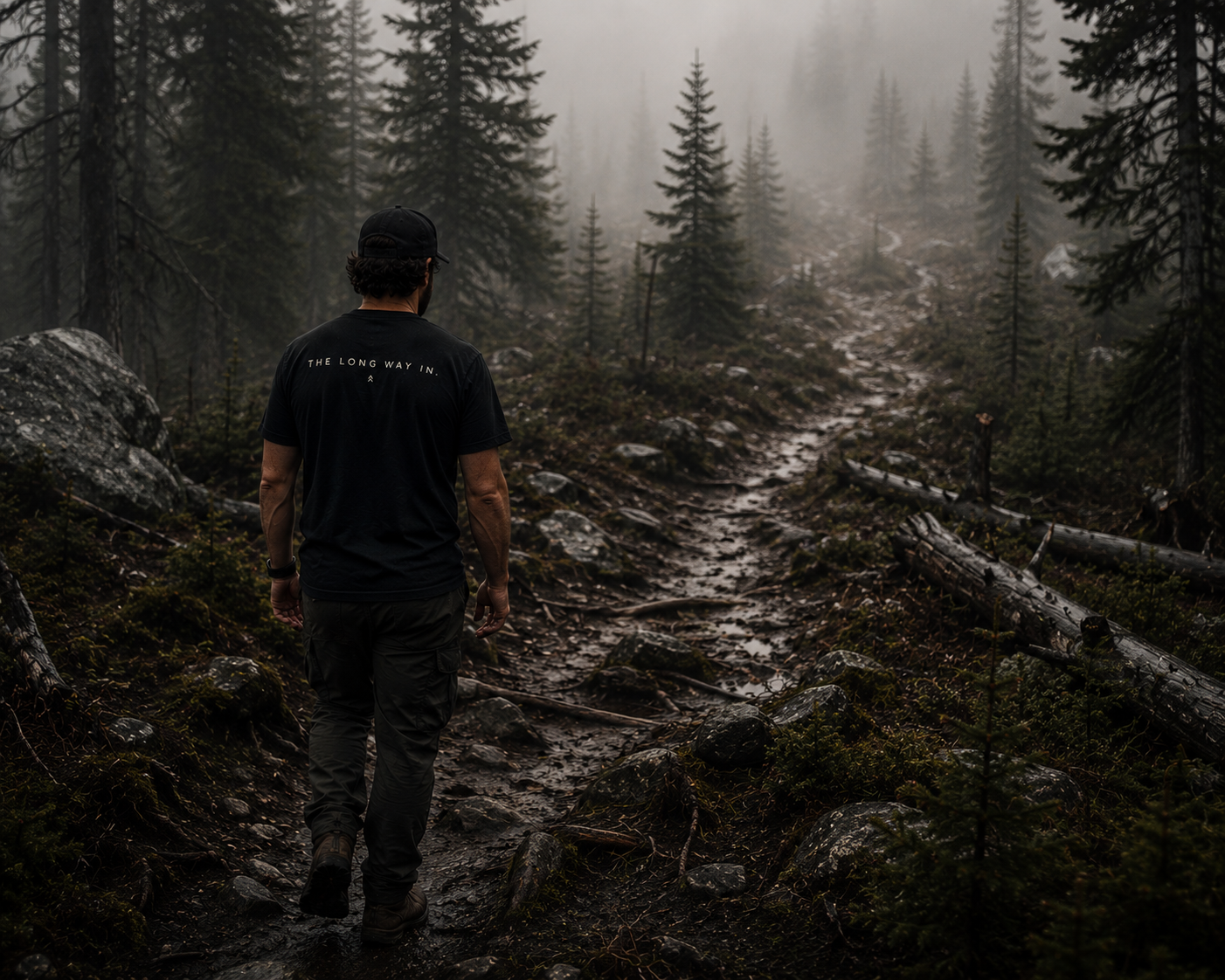Person wearing The Long Way In typography shirt by Black Timber Goods on a forest trail.