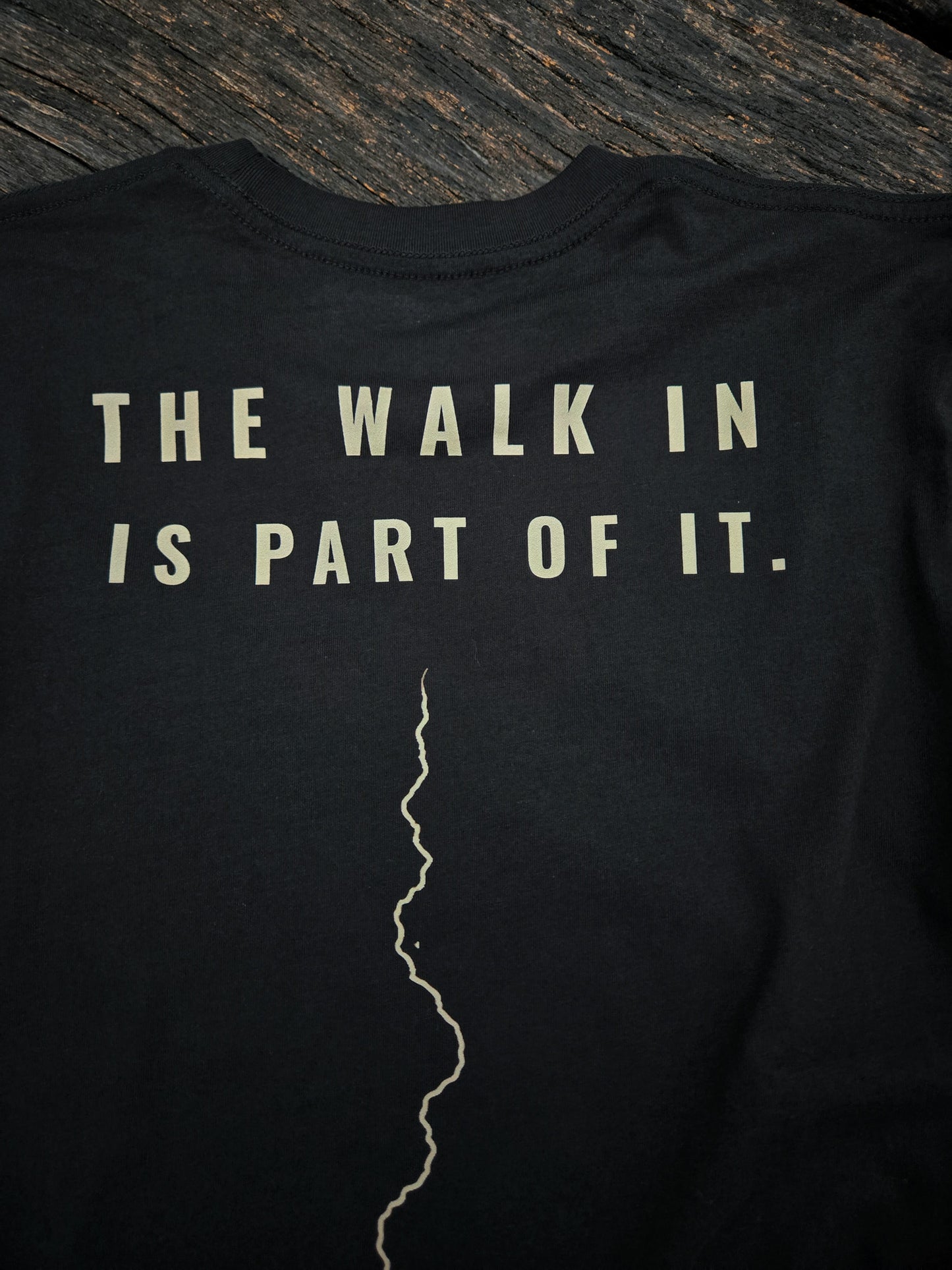 Person wearing The Walk In Is Part Of It trail shirt by Black Timber Goods on a wooded trail.